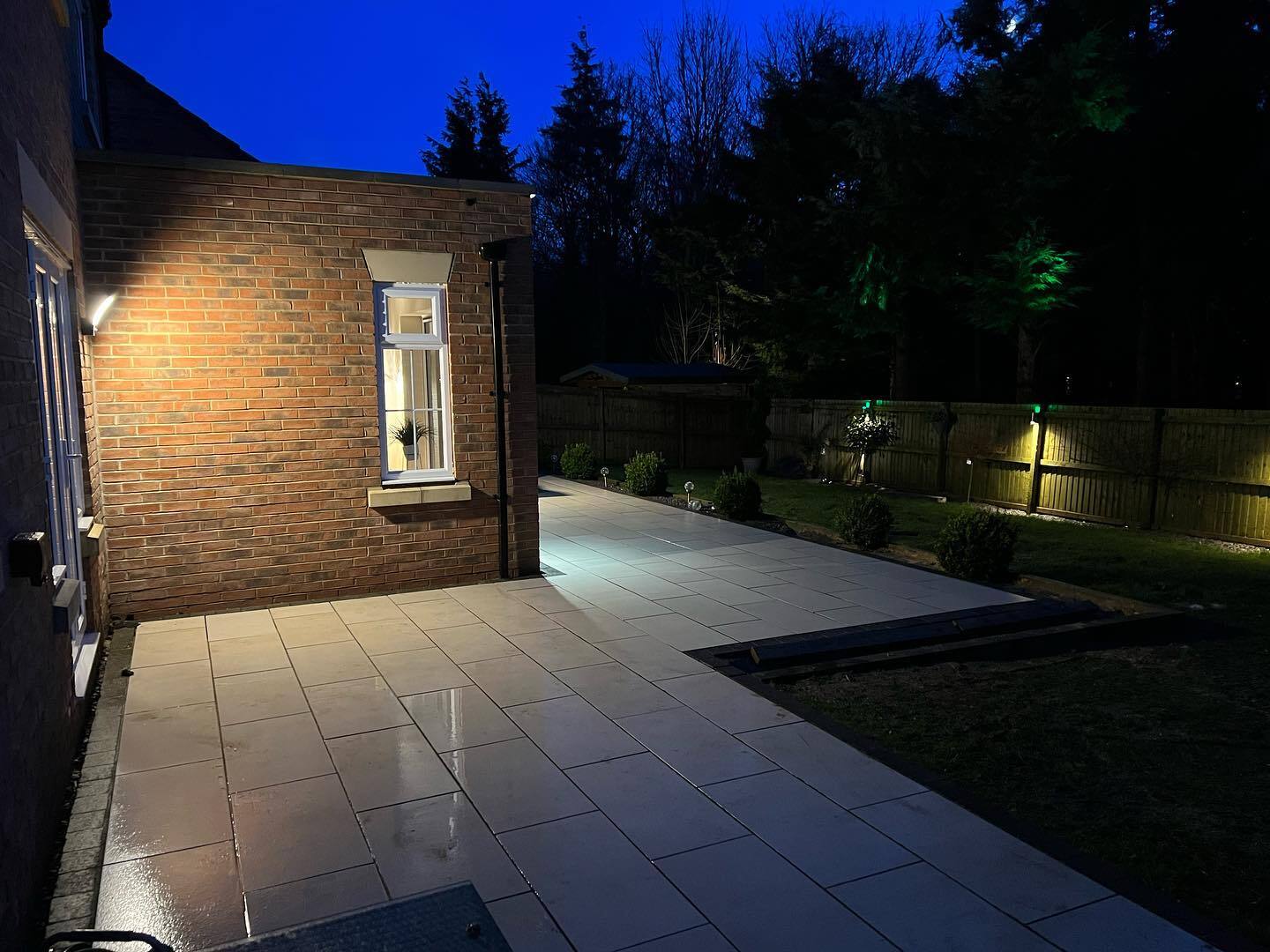 Modern single-storey house extension illuminated at night, featuring large glass doors and warm exterior lighting