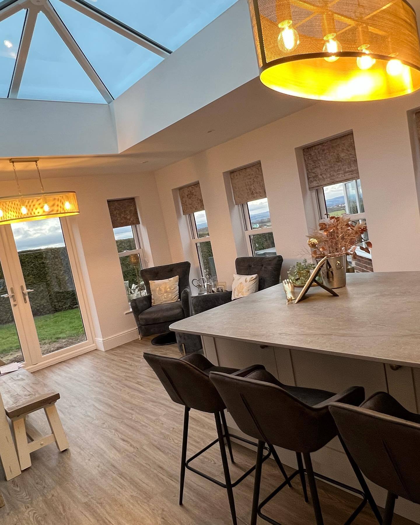 Interiro shot of a sunroom designed and constructed by Construct North. Warm interior lightingwith two arm chairs and a dinning room table with flowers in a vase